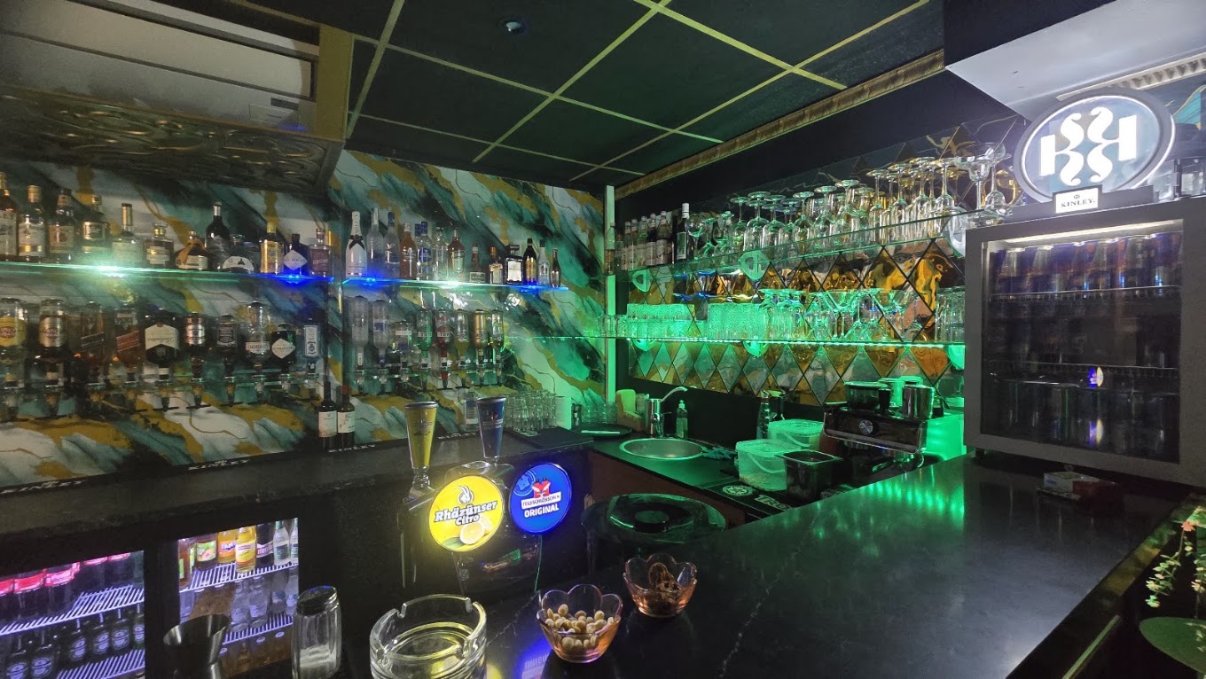 Bartresen der Grün Lounge mit grüner Beleuchtung, Gläsern und Spirituosen