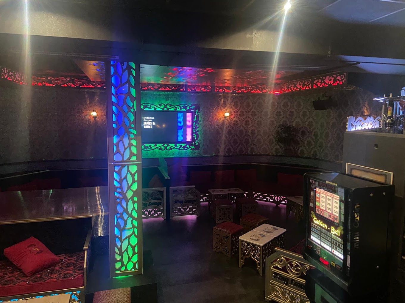 Farbig beleuchteter Lounge-Bereich mit roten Polstersofas und Spielautomat